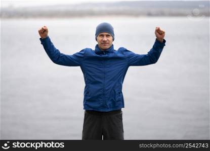 man standing near lake with arms air