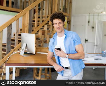 Man standing next to his desk in office