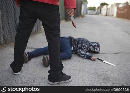 Man standing next to stabbed man lying on ground