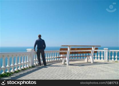 Man standing on balcony and look on the sea horizon at day. Calm and relax composition.