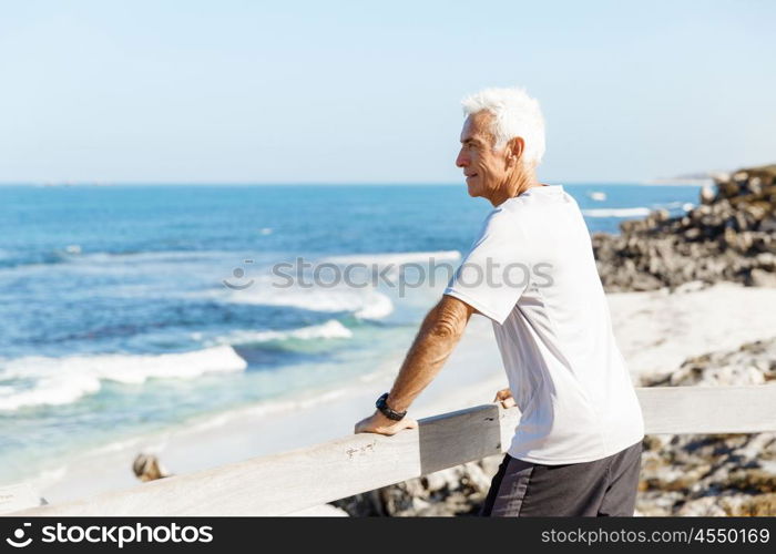 Man standing on beach in sports wear. Man standing on beach in sports wear looking fit and happy