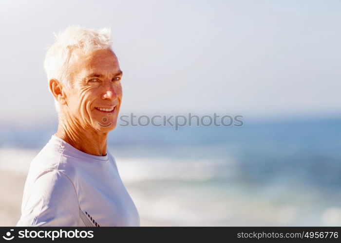 Man standing on beach in sports wear. Man standing on beach in sports wear looking fit and happy