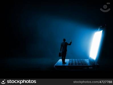 Man standing on big laptop. Rear view of businessman with suitcase standing on keyboard of big laptop