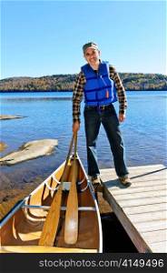 Man standing on dock with canoe on Lake of Two Rivers, Ontario, Canada
