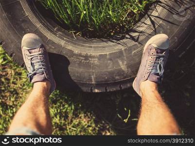 Man standing on old tire, tinted photo
