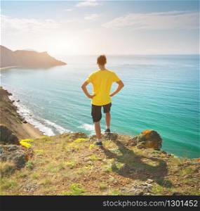 Man standing on sea and mountain landscape. Conceptual and emotional scene.