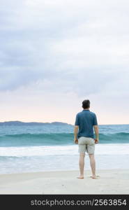 Man standing on the beach contemplating the sea