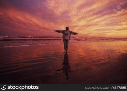 Man standing on the beach with his arms outstretched, Texas, USA