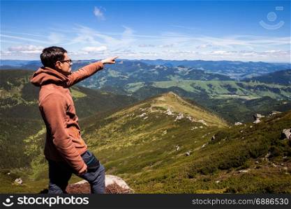 Man standing on the mountain top and pointing on horizon