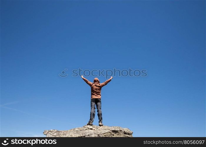 Man standing on the top of the mountain over blue sky