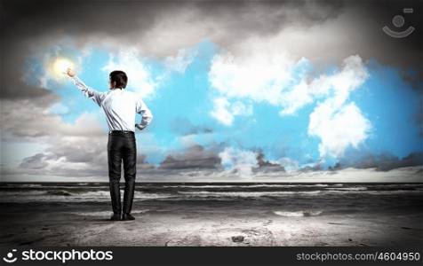 Man standing with back touching sun. young man standing with back touching sun against clouds background