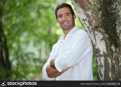 Man standing with his arms crossed under a large tree