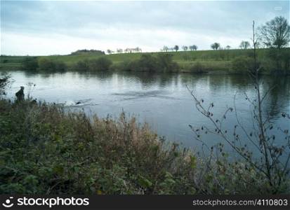 Man stands at side of river in Berwickshire, Scotland