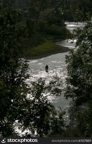 Man stands fishing in river of Berwickshire, Scotland