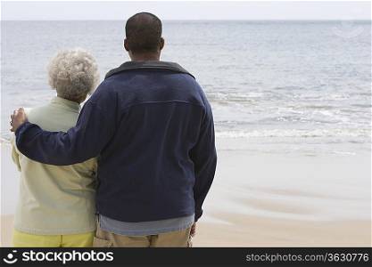 Man stands with his arm round a woman at waters edge