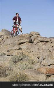 Man stands with mountain bike on rocky outcrop