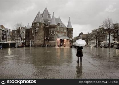 Man stands with umbrella in town square
