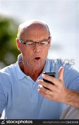 Man staring at his mobile phone is disbelief