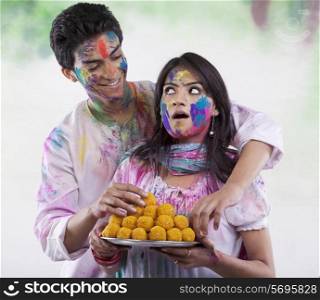 Man stealing a laddoo from a tray