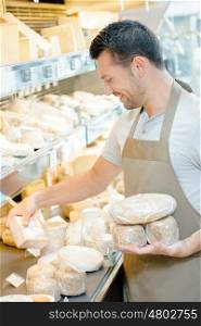 Man stocking the shelves in a cheese shop