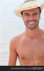 Man stood on the beach wearing straw hat