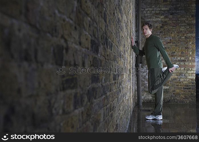 Man stretching against wall