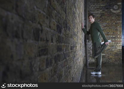 Man stretching against wall