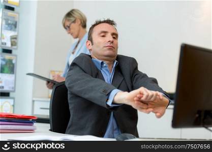 man stretching at his desk in estate agents office