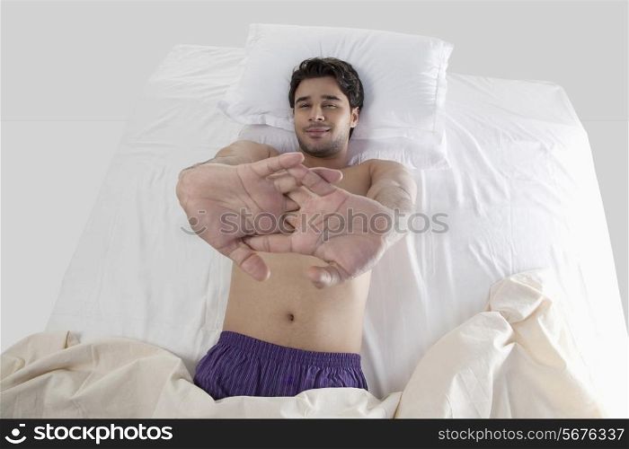 Man stretching his arms in bed
