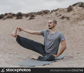 man stretching his leg while doing yoga outdoors