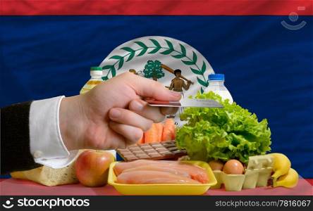 man stretching out credit card to buy food in front of complete wavy national flag of belize