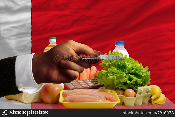 man stretching out credit card to buy food in front of complete wavy national flag of bahrain