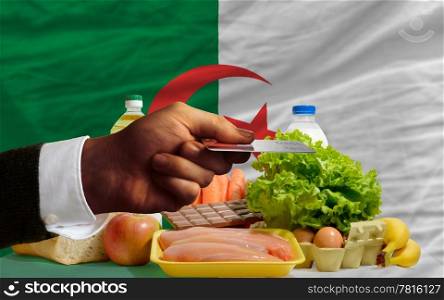 man stretching out credit card to buy food in front of complete wavy national flag of algeria