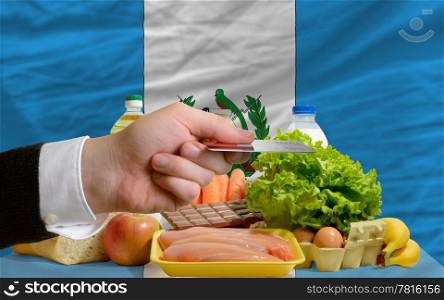 man stretching out credit card to buy food in front of complete wavy national flag of guatemala
