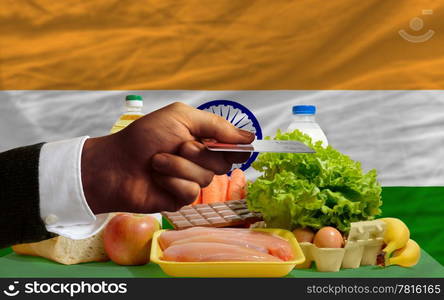 man stretching out credit card to buy food in front of complete wavy national flag of india