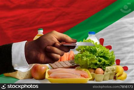 man stretching out credit card to buy food in front of complete wavy national flag of katanga
