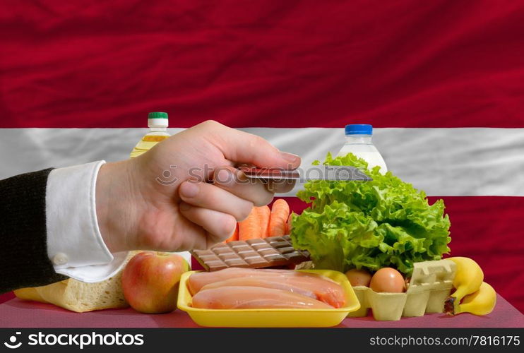 man stretching out credit card to buy food in front of complete wavy national flag of latvia