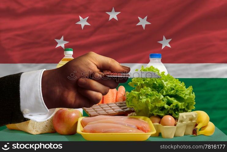 man stretching out credit card to buy food in front of complete wavy national flag of maghreb