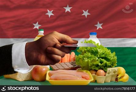man stretching out credit card to buy food in front of complete wavy national flag of maghreb