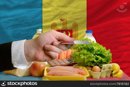 man stretching out credit card to buy food in front of complete wavy national flag of moldova