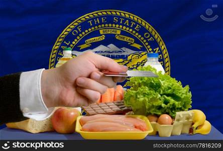 man stretching out credit card to buy food in front of complete wavy american state flag of nebraska