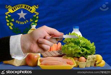 man stretching out credit card to buy food in front of complete wavy american state flag of nevada