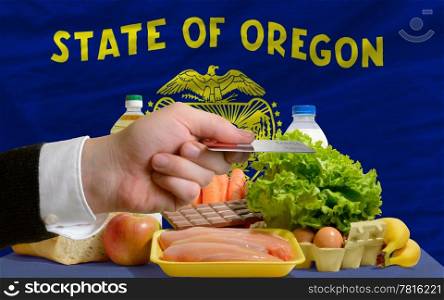man stretching out credit card to buy food in front of complete wavy american state flag of oregon