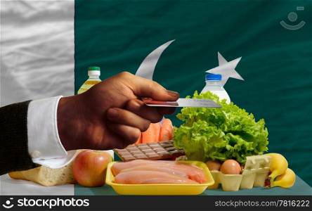 man stretching out credit card to buy food in front of complete wavy national flag of pakistan