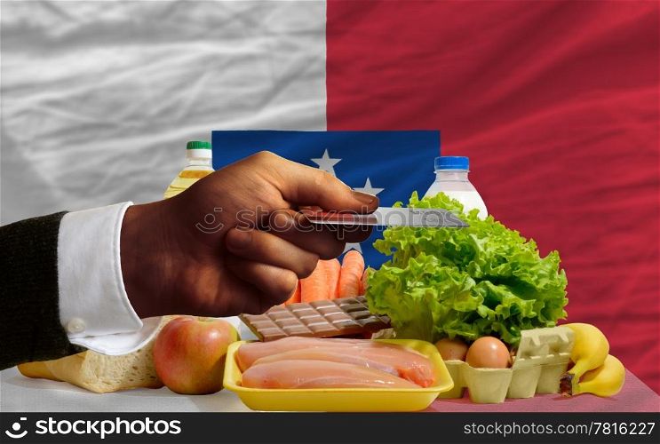man stretching out credit card to buy food in front of complete wavy national flag of franceville