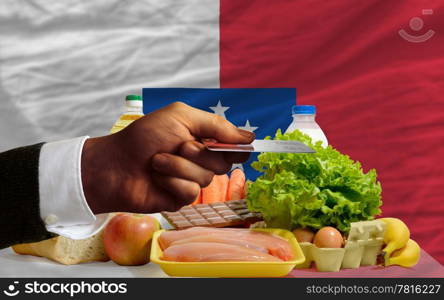 man stretching out credit card to buy food in front of complete wavy national flag of franceville