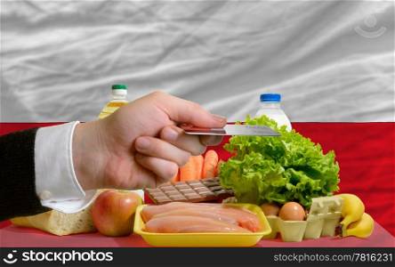 man stretching out credit card to buy food in front of complete wavy national flag of poland