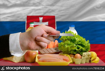 man stretching out credit card to buy food in front of complete wavy national flag of russia