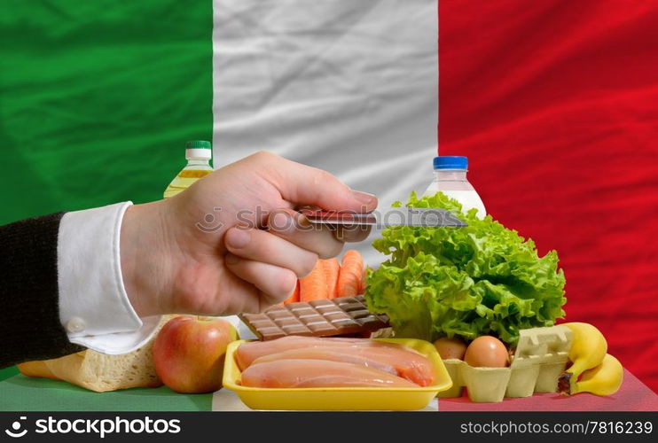 man stretching out credit card to buy food in front of complete wavy national flag of italy