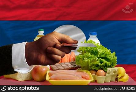 man stretching out credit card to buy food in front of complete wavy national flag of laos